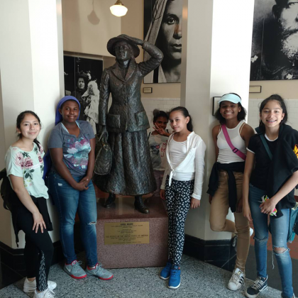 students pose with statue of first female immigrant at Ellis Island National Museum