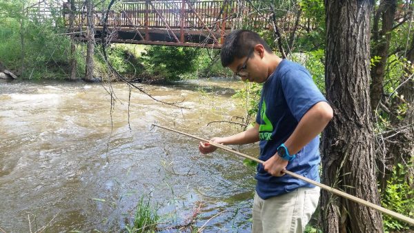 Groundwork Denver Blue Team member collecting water sample on Bear Crek